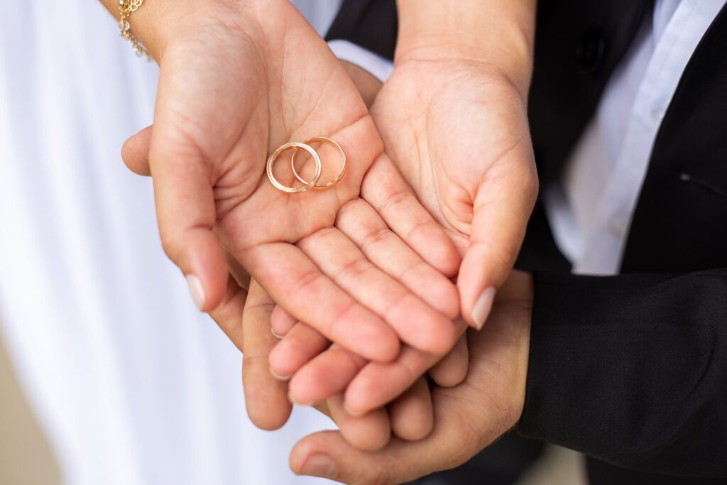 Two hands cupped together holding a pair of gold wedding rings