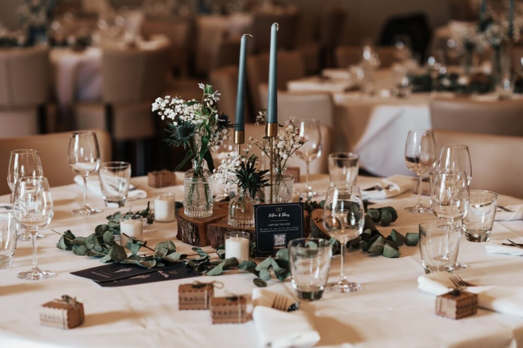 Wedding reception tables decorated with candles, glassware and floral centrepieces
