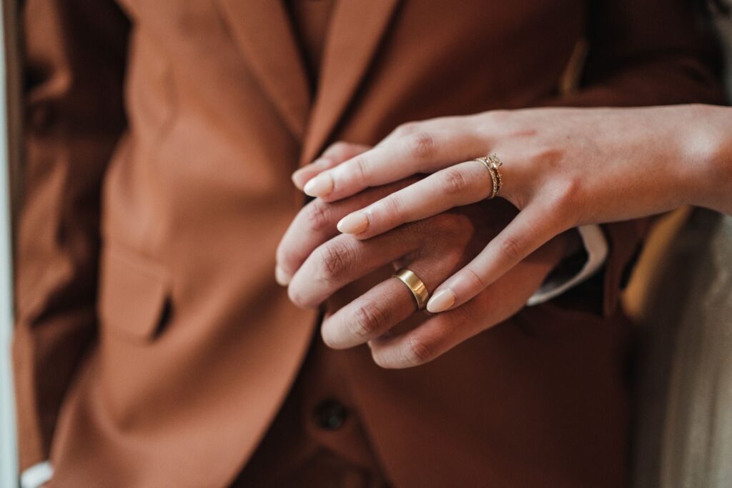 Close-up of a couple holding hands, both wearing wedding rings